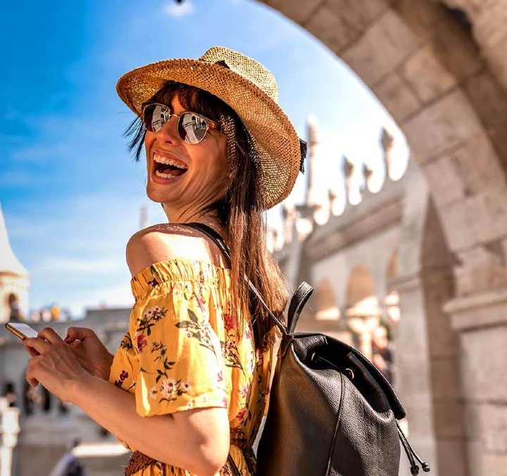 Viajante de chapéu e mochila sorrindo durante um passeio, na campanha da YOUCAN Travel.